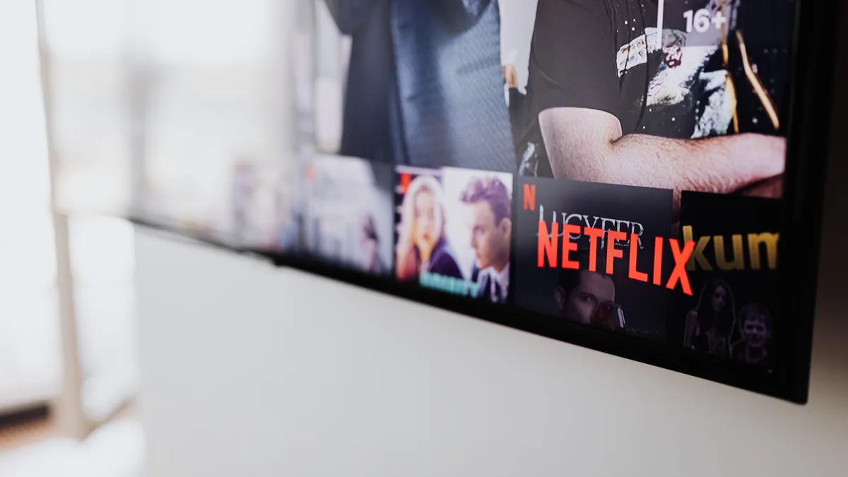 Telecomandă îndreptată spre un televizor care afișează o platformă de streaming