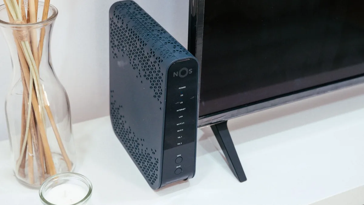 Router wireless pe un birou, lângă un monitor
